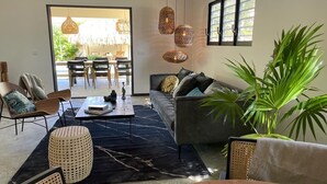 A modern living room with a sofa, chairs, a coffee table, and hanging lights. - Belnem Garden Residence (Kralendijk)