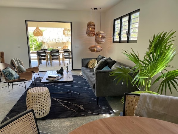 A modern living room with a sofa, chairs, a coffee table, and hanging lights.