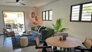 A modern living room with a sofa, coffee table, and dining area with chairs and a table. - Belnem Garden Residence (Kralendijk)