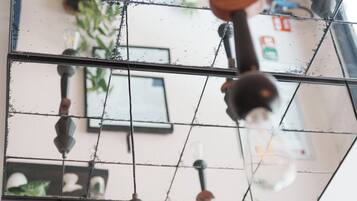 Una habitación con un espejo grande que refleja una zona de cocina, un lámpara colgante y una planta.