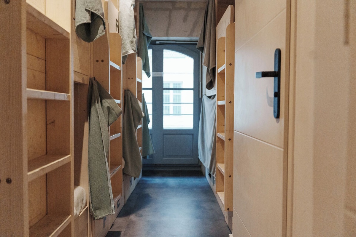A narrow hallway with wooden lockers on both sides and a door at the end.