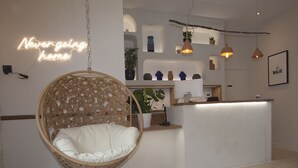 Un interior acogedor con una silla colgante, un mostrador de recepción y un letrero de neón.