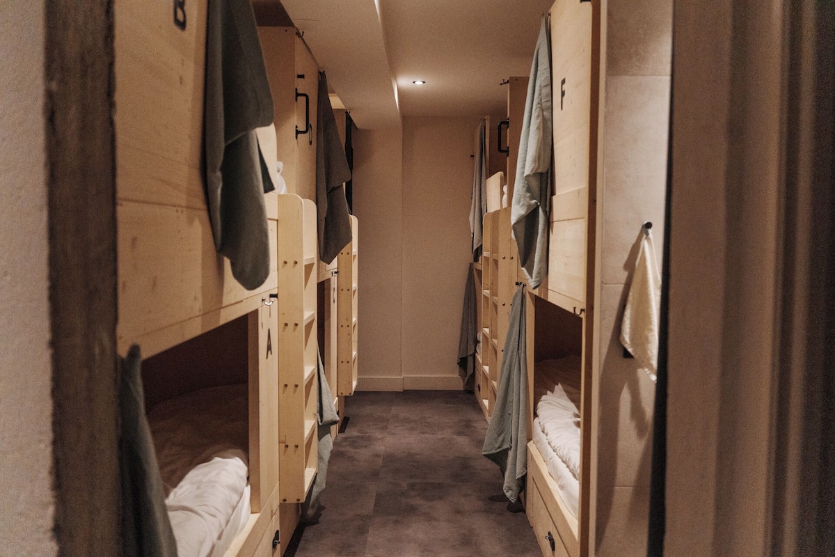 A narrow corridor with bunk beds on either side, each with a towel hanging on the side.