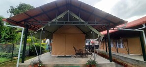 Un espacio al aire libre cubierto con una mesa y sillas, rodeado de plantas en macetas.