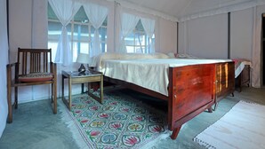 Un dormitorio con cama de madera, una silla, una mesita de noche y una alfombra estampada.