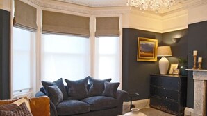 A living room with a dark-colored sofa, a coffee table, and a fireplace. - Beaufort House, Lymington Town Centre (Lymington)