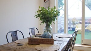 A wooden dining table with a rustic design, a vase with green plants, and a wooden sign. - Beaufort House, Lymington Town Centre (Lymington)