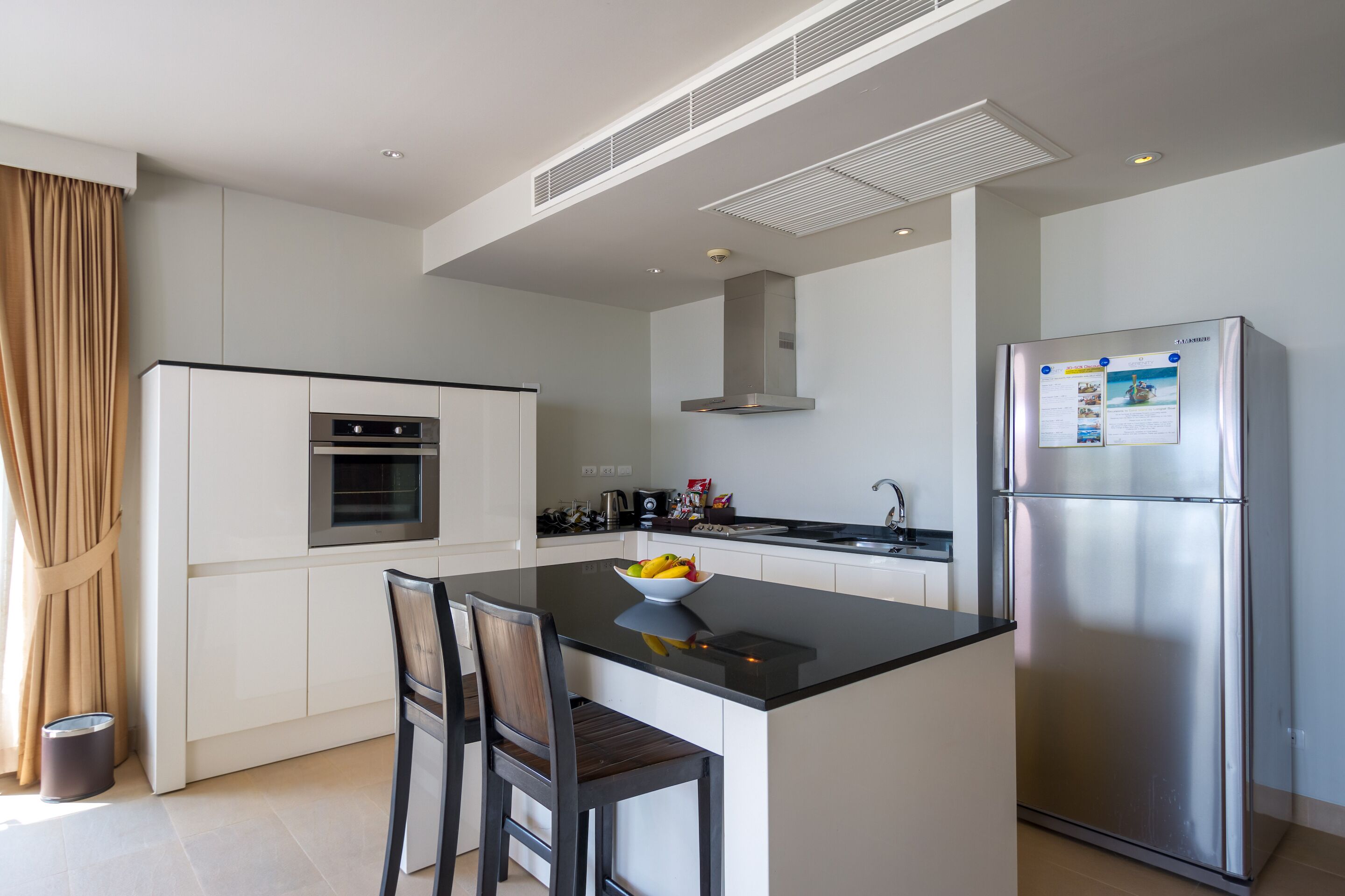 Une cuisine moderne dotée d’un îlot central, d’appareils électroménagers en acier inoxydable et d’un four encastré.