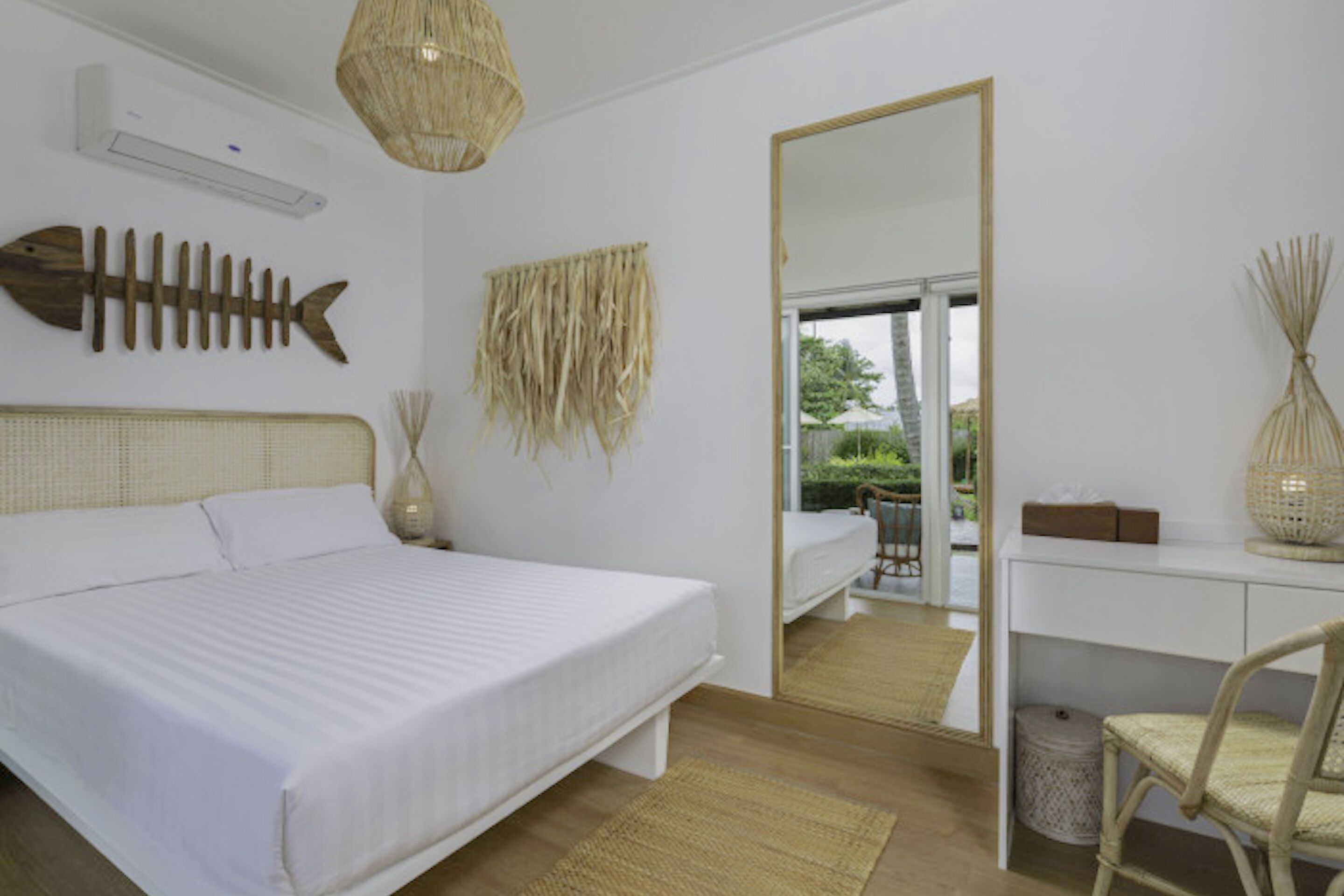 Une chambre avec un grand lit, un bureau, une chaise, un miroir et une vue sur l’extérieur.