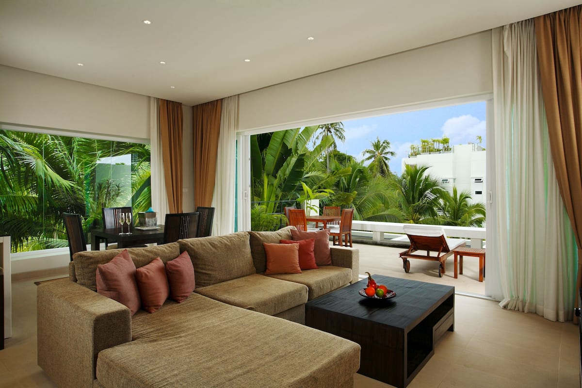 A modern living room with a large sofa, a coffee table, and a dining area with chairs and a table.