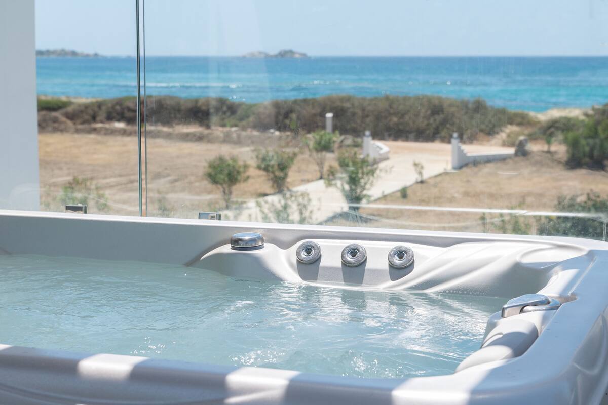 A hot tub with a view of the ocean and dry landscape.