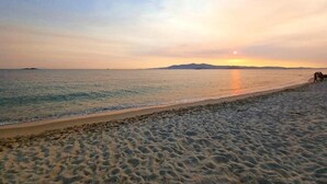 A beach with a calm sea, a clear sky, and a distant landmass. - Sea Lilies Suites (Naxos)