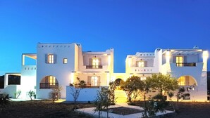A modern white building with multiple balconies and a well-lit entrance. - Sea Lilies Suites (Naxos)
