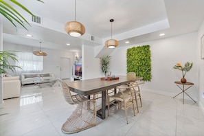 A spacious dining area with a long wooden table, wicker chairs, and hanging rattan light fixtures.