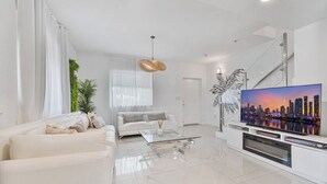 Ein modernes Wohnzimmer mit Sofa, Couchtisch, Fernseher und Treppe.