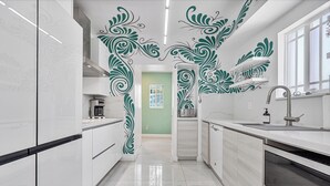 Eine moderne Küche mit weißen Schränken, einer schwarzen Arbeitsplatte und dekorativer Wandkunst in Grün.