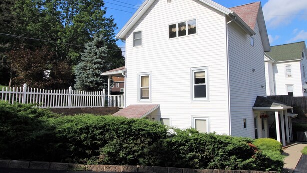 A two-story white house with a front porch and a small attached garage. - Cooperstown Baseball Rentals - Team Basemen (Oneonta)