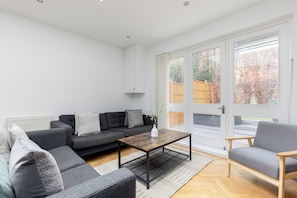 Ett modernt vardagsrum med en grå soffa, ett soffbord i trä och en grå fåtölj.