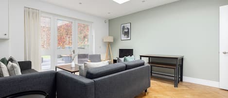 A modern living room with a grey sofa, a small table, and a lamp.