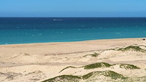 A beach with clear blue water and sandy dunes.