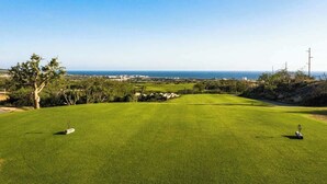 A golf course with a clear view of the ocean and distant buildings.