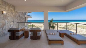 Un área de descanso moderna con una pared de piedra, una mesa de billar y sillones con vistas a la playa y al océano.