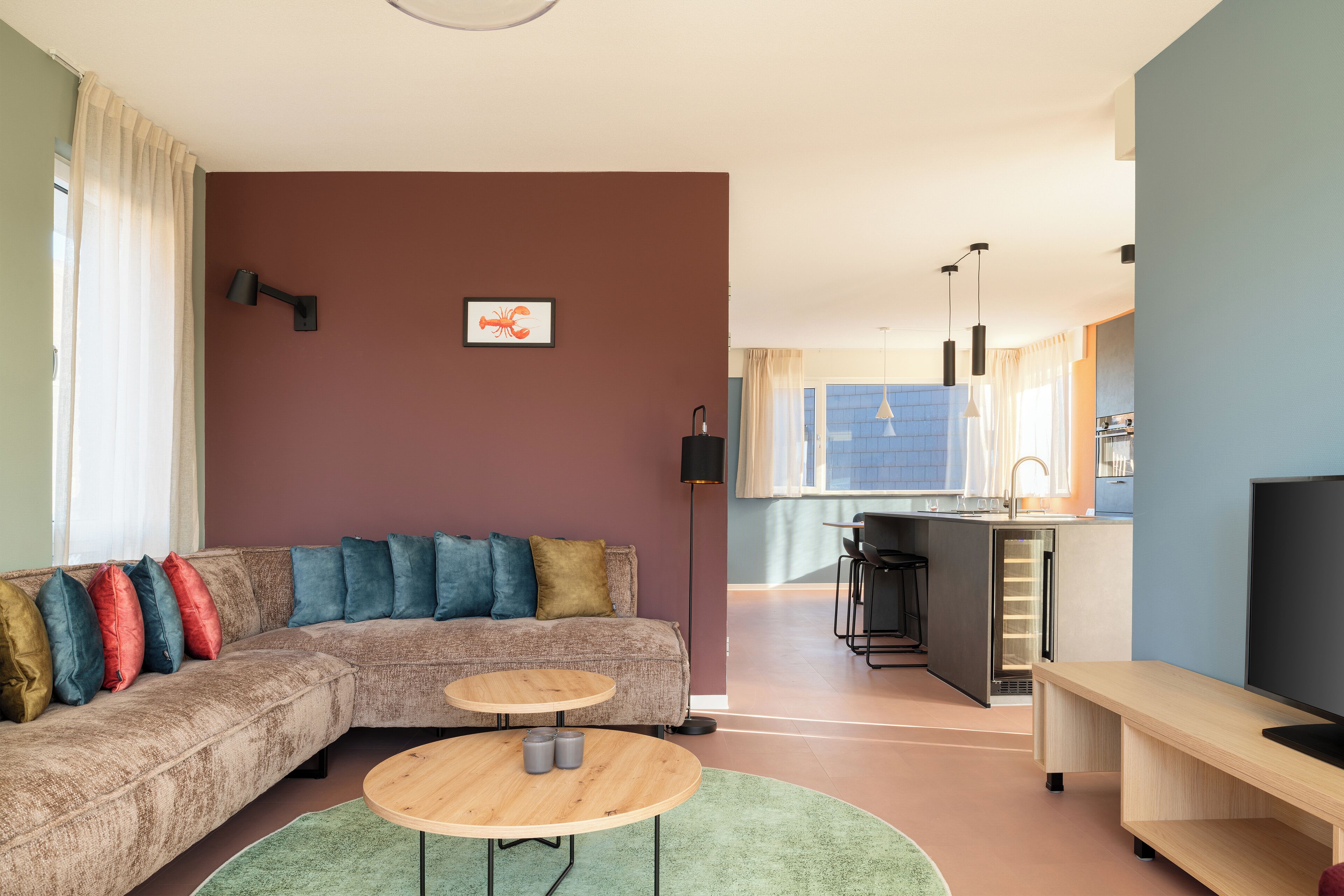 A modern living room with a sectional sofa, a round coffee table, and a kitchen area in the background.