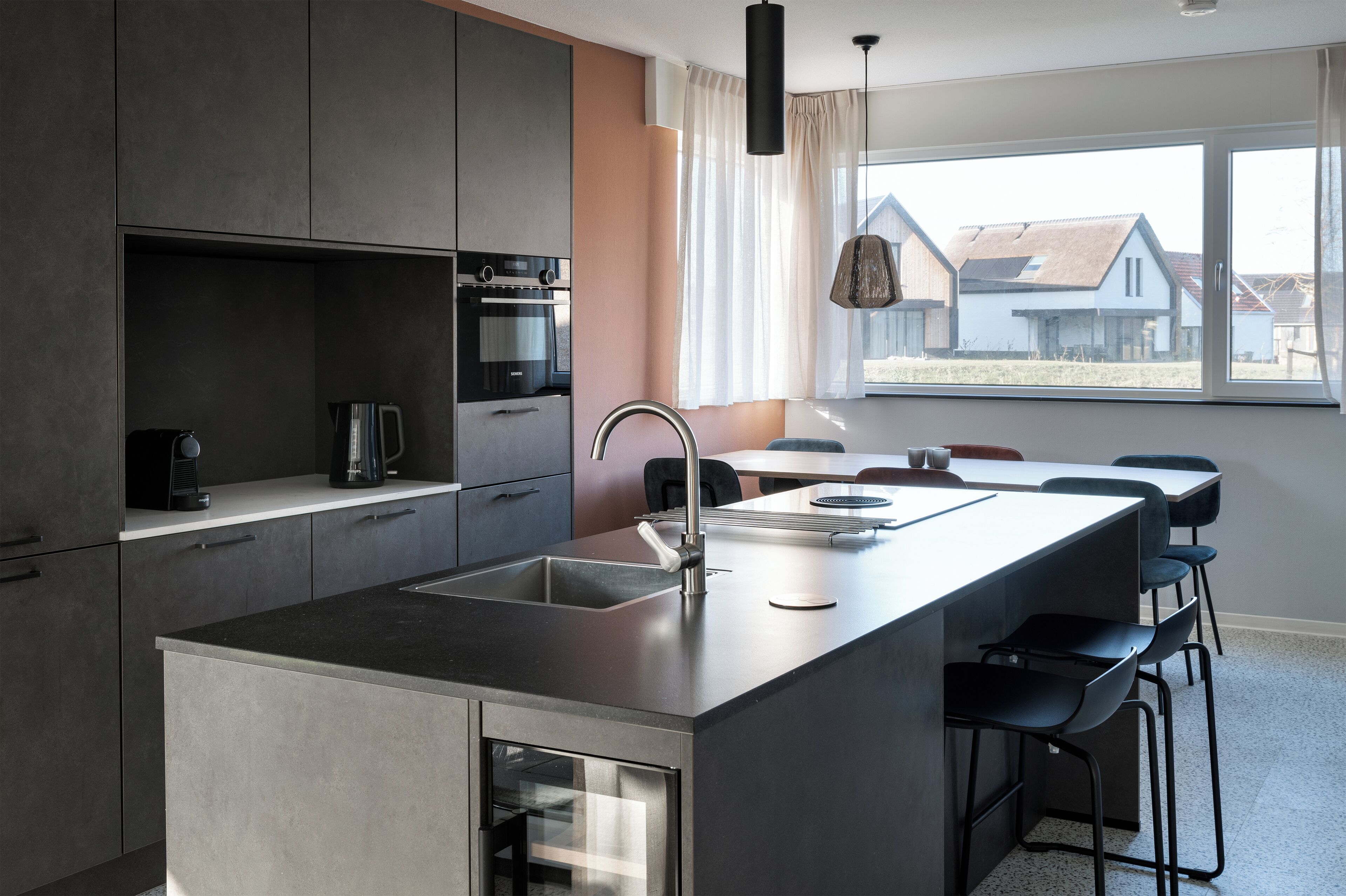 Una cocina moderna con una isla central, electrodomésticos integrados y un amplio ventanal con vistas al exterior.