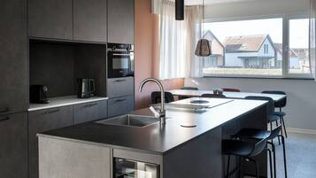 Una cocina moderna con una isla central, electrodomésticos integrados y un amplio ventanal con vistas al exterior.