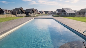 A swimming pool with a wooden deck, surrounded by houses with gabled roofs. - Dormio resort Nieuwvliet-Bad (Nieuwvliet)