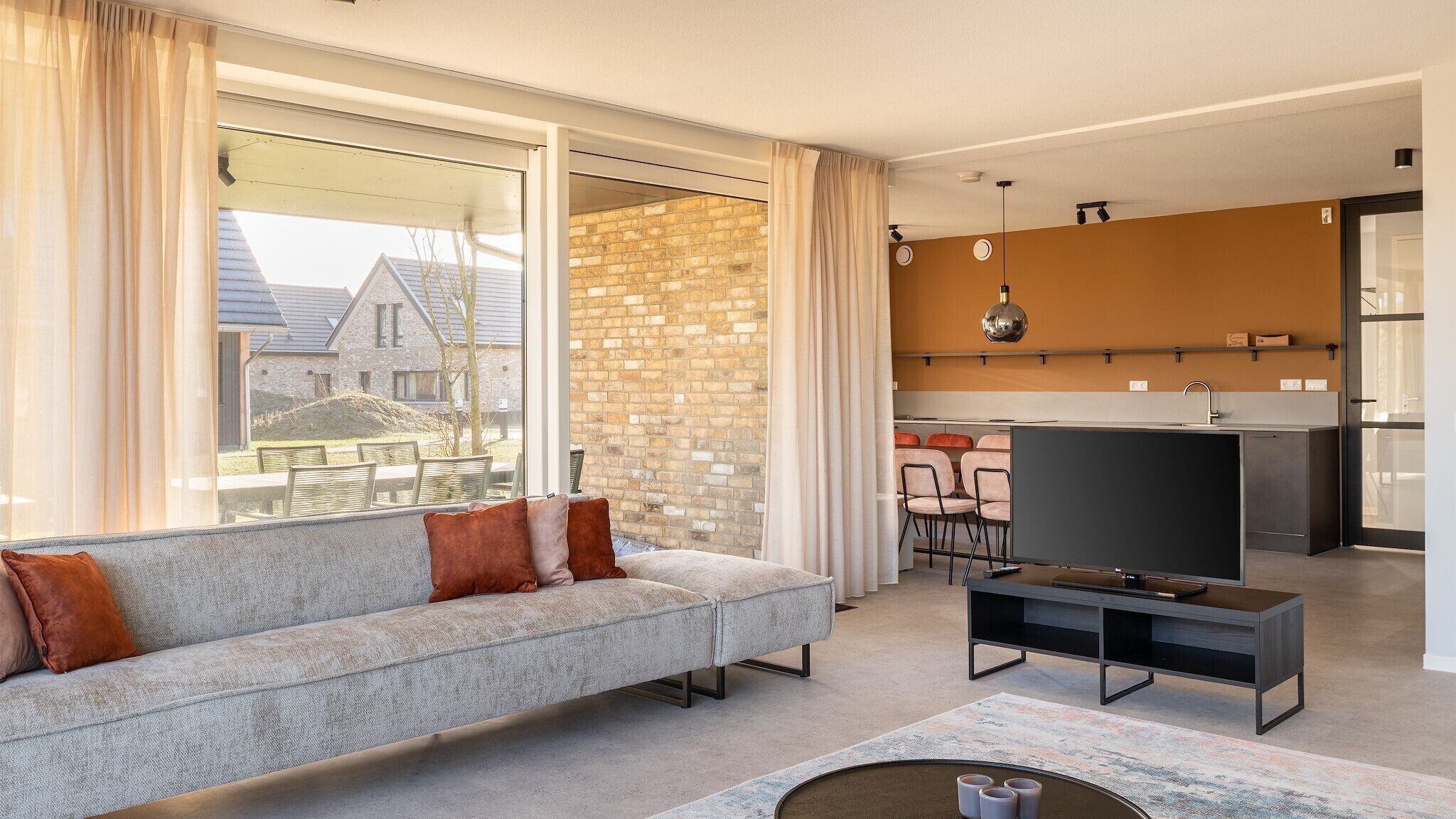 A modern living room with a grey sofa, a flat-screen TV, and a coffee table.