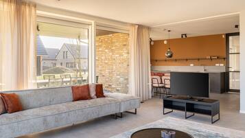 A modern living room with a grey sofa, a flat-screen TV, and a coffee table.