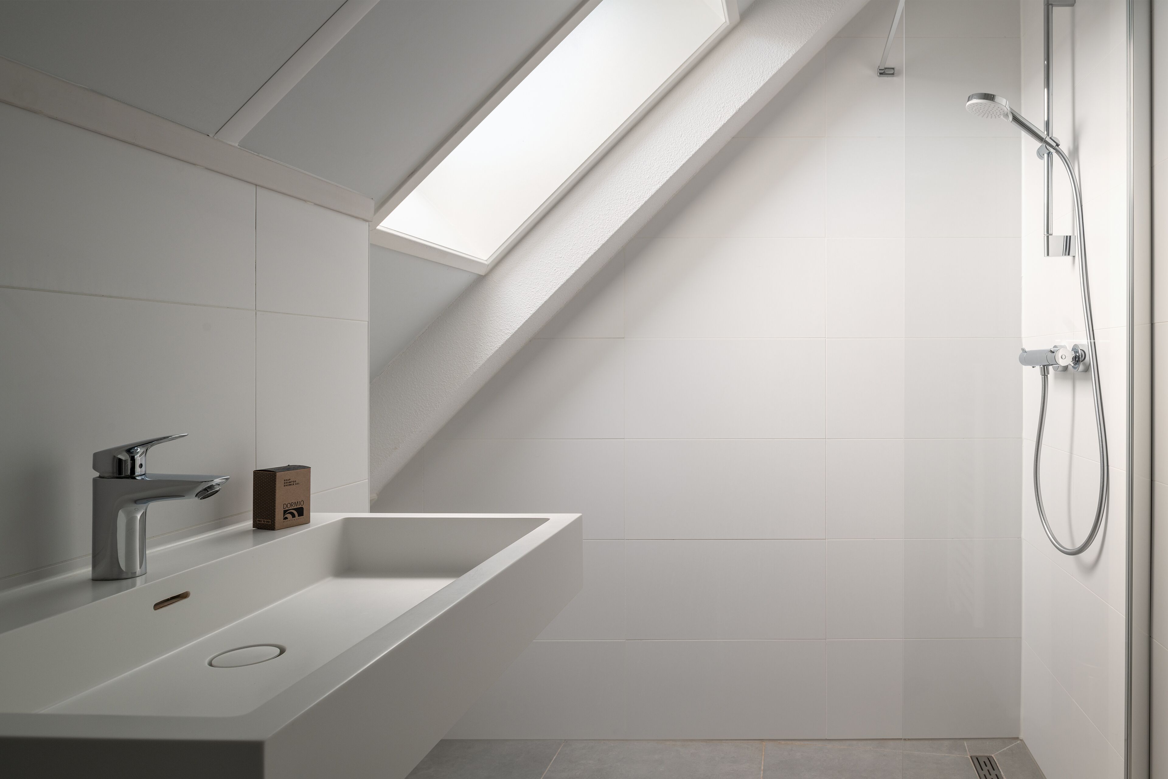 Ein modernes Badezimmer mit Dachfenster, Dusche und Waschbecken mit Armatur.