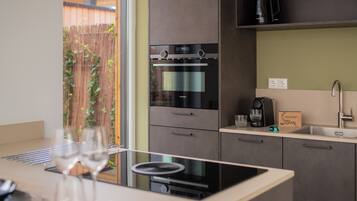 A modern kitchen with built-in appliances, a sink, and a window overlooking a garden.