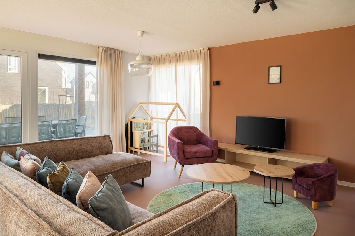 Una sala de estar con un sofá, sillones, un televisor y una alberca para bebés.