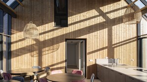 A modern kitchen with wooden walls, a large window, and a dining area with a round table and chairs. - Dormio resort Nieuwvliet-Bad (Nieuwvliet)