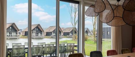 A dining area with a view of a water body and houses.