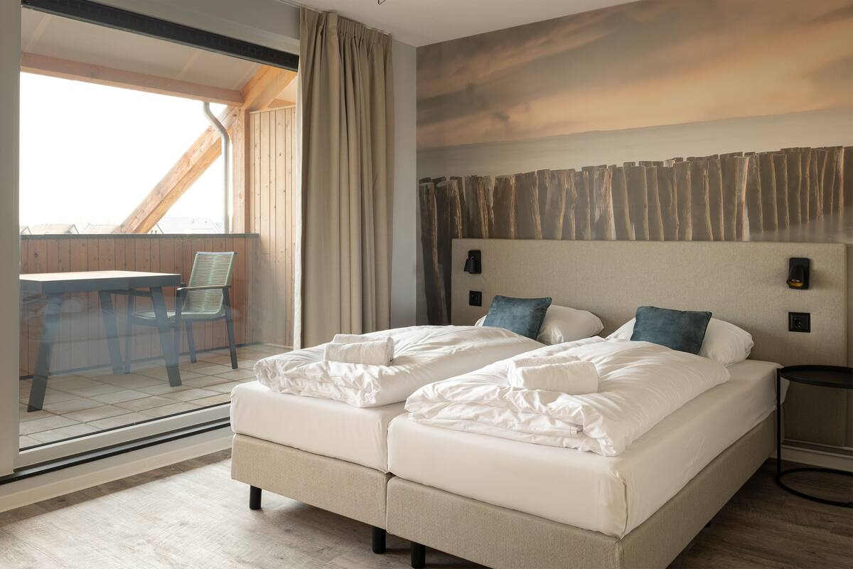 Habitación de hotel con una cama grande, un escritorio y vistas a través de una ventana.