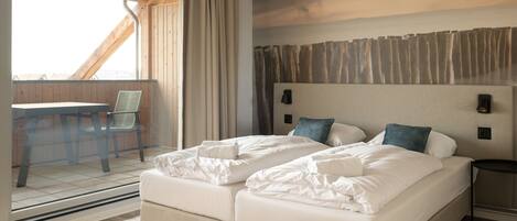 Ein Hotelzimmer mit einem großen Bett, einem Schreibtisch und Blick durch ein Fenster.