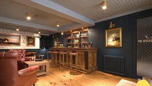 A bar area with wooden flooring, leather seating, and a bar counter with stools. - The Swan - A Colombo Edition Hotel (Ely)