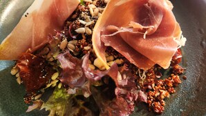 A close-up of a dish with various ingredients including greens, nuts, and slices of meat. - The Swan - A Colombo Edition Hotel (Ely)