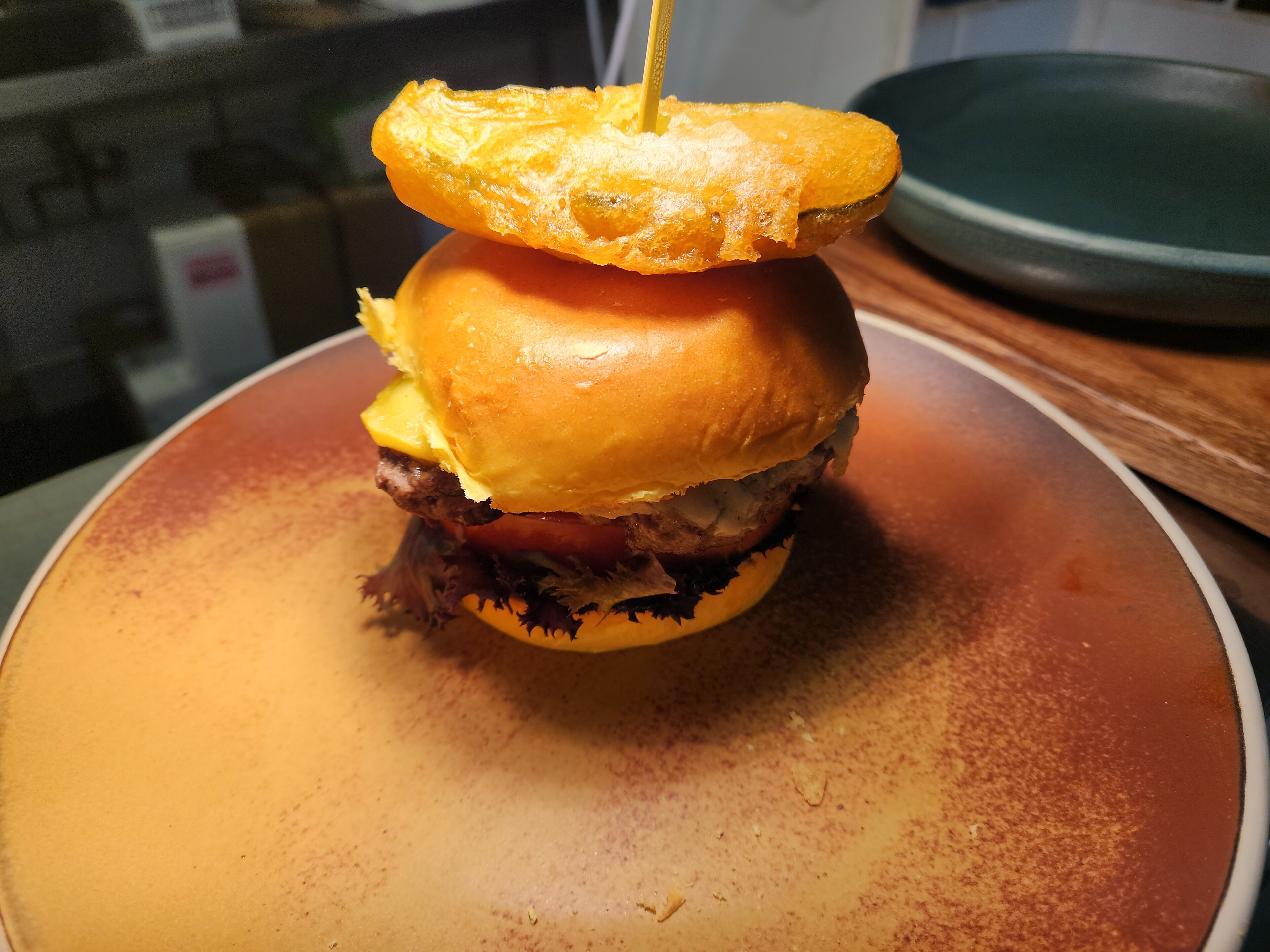 A burger with a toothpick on top, placed on a plate.
