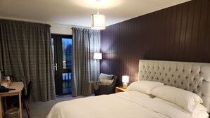 A hotel room with a large bed, a desk, and a chair. There is a door leading to an outdoor area. - The Swan - A Colombo Edition Hotel (Ely)