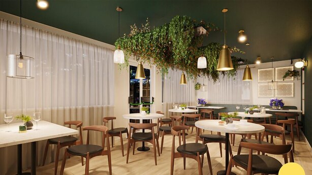 A restaurant interior with round tables, wooden chairs, hanging plants, and pendant lighting. - The Swan - A Colombo Edition Hotel (Ely)