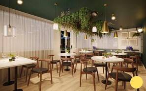 A restaurant interior with round tables, wooden chairs, hanging plants, and pendant lighting. - The Swan - A Colombo Edition Hotel (Ely)