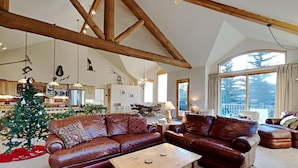A spacious living room with a high ceiling, leather sofas, a coffee table, and a Christmas tree. - Beautiful home with stunning views, a hot tub, and a pool table ready! (Dillon)