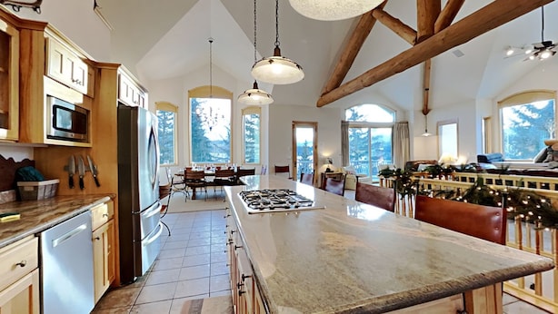 A spacious kitchen with a large island, wooden beams, and large windows. - Beautiful home with stunning views, a hot tub, and a pool table ready! (Dillon)