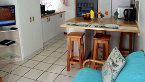 A compact kitchen with a dining area, a TV, and a sofa. - Sea Why is a self-catering apartment in Nature's Valley , 5 min from the beach (Plettenberg Bay)
