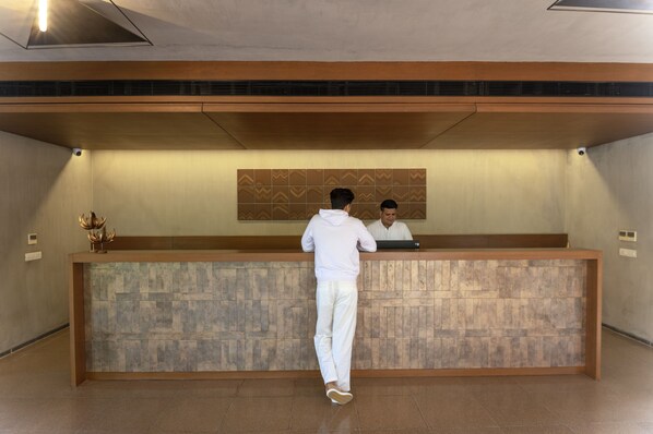 A reception desk with a patterned wall and a ceiling vent.
