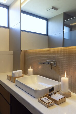 A modern bathroom with a large rectangular sink, a mirror, and a window above the sink.